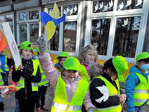Mit FRÖBEL-Caps, Westen und Schildern warten die Kinder auf den Start